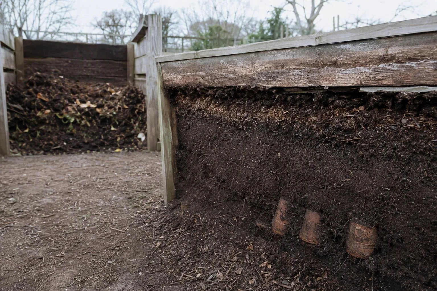 Raised bed cross-section showing mineral soil, mature compost, coarse organic material, and native soil below.
